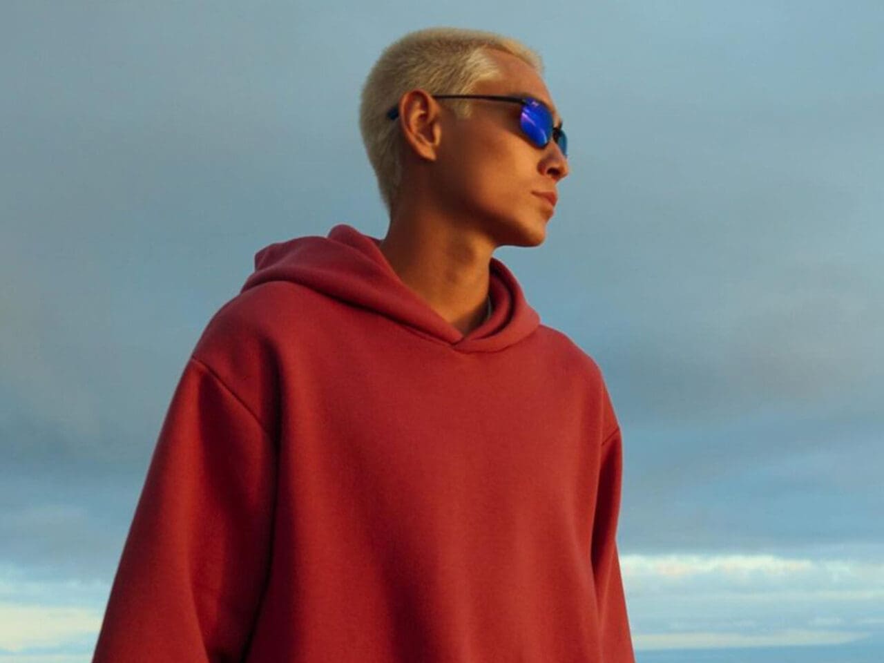 Evan Mock wearing a blue and black Maui Jim and red oversized hoodie