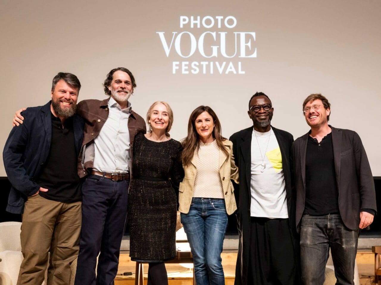 A big group of people photographed together in front of a wall that reads 