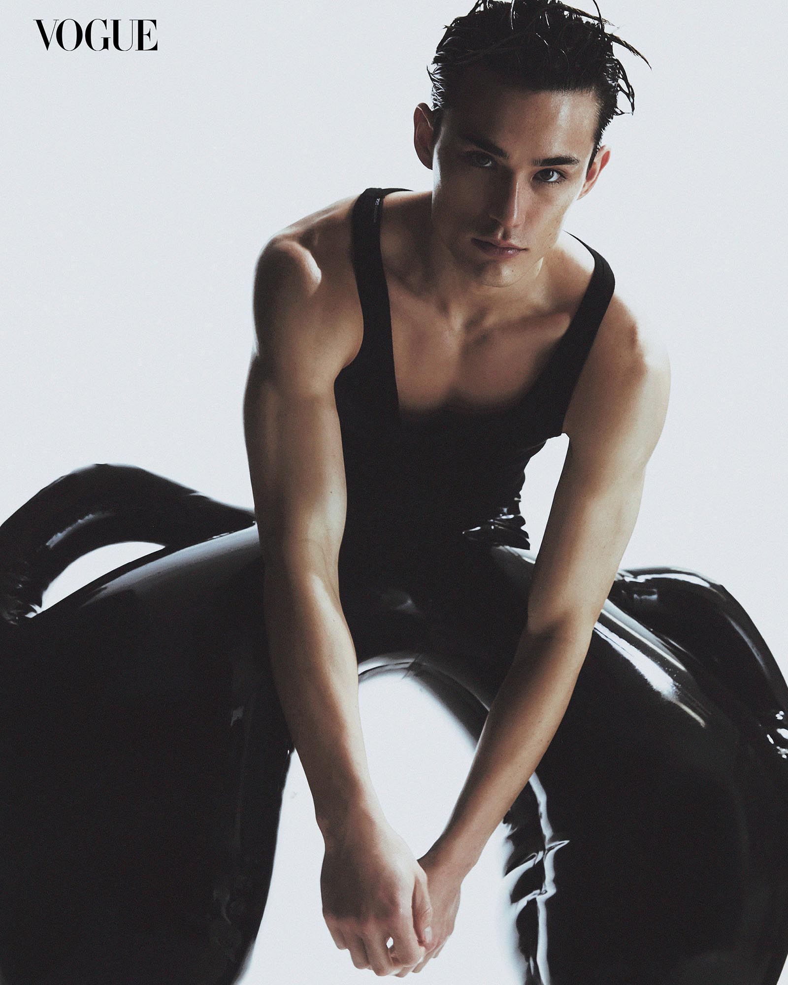 An image of Alex Schlab dressed in a black tank top and latex pants on a white background.