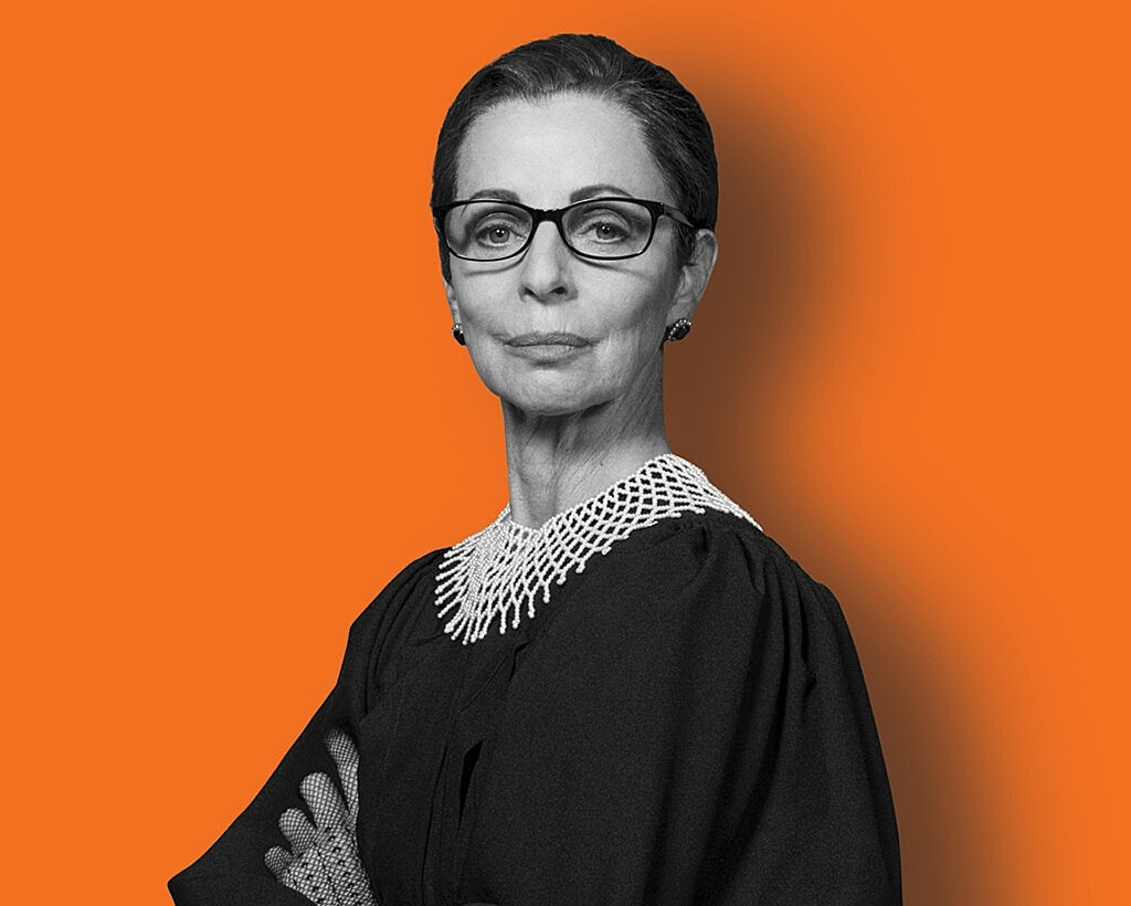 A woman portraying Ruth Bader Ginsburg, wearing black glasses and robes against an orange background.