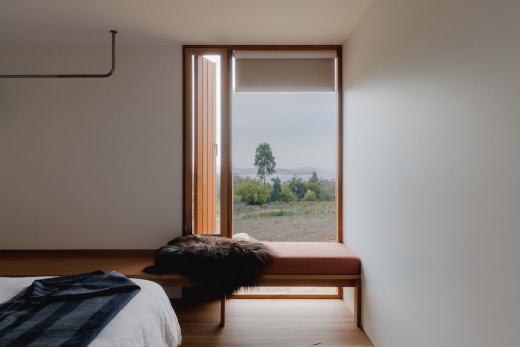 Minimalist bedroom with no built-in furniture except a clothing rail, photographed for green magazine issue 105: High and Dry by Tim Clark Studio.