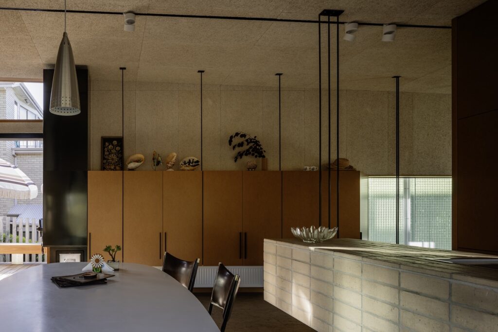 Kitchen–dining with pendant lighting, cork-lined walls and cabinetry displaying collected pieces, photographed for green magazine issue 105: Timeless by Trevor Mein.
