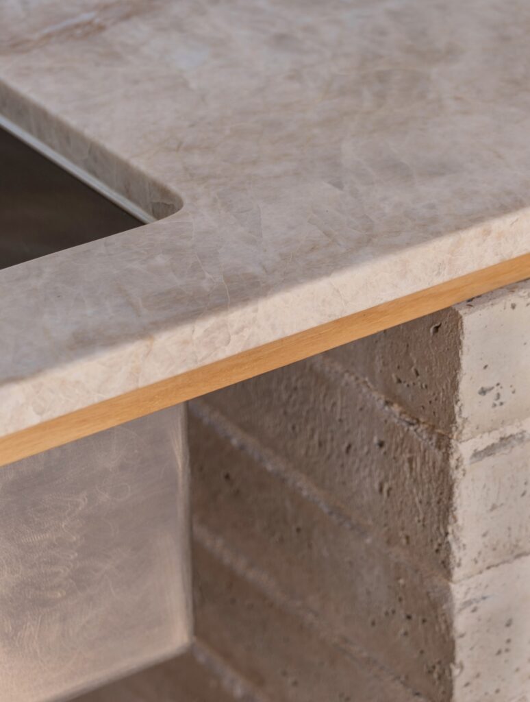Kitchen bench crafted from stone, blackbutt and sustainable bricks, photographed for green magazine issue 105: Southern Calm by Joanne Ly.