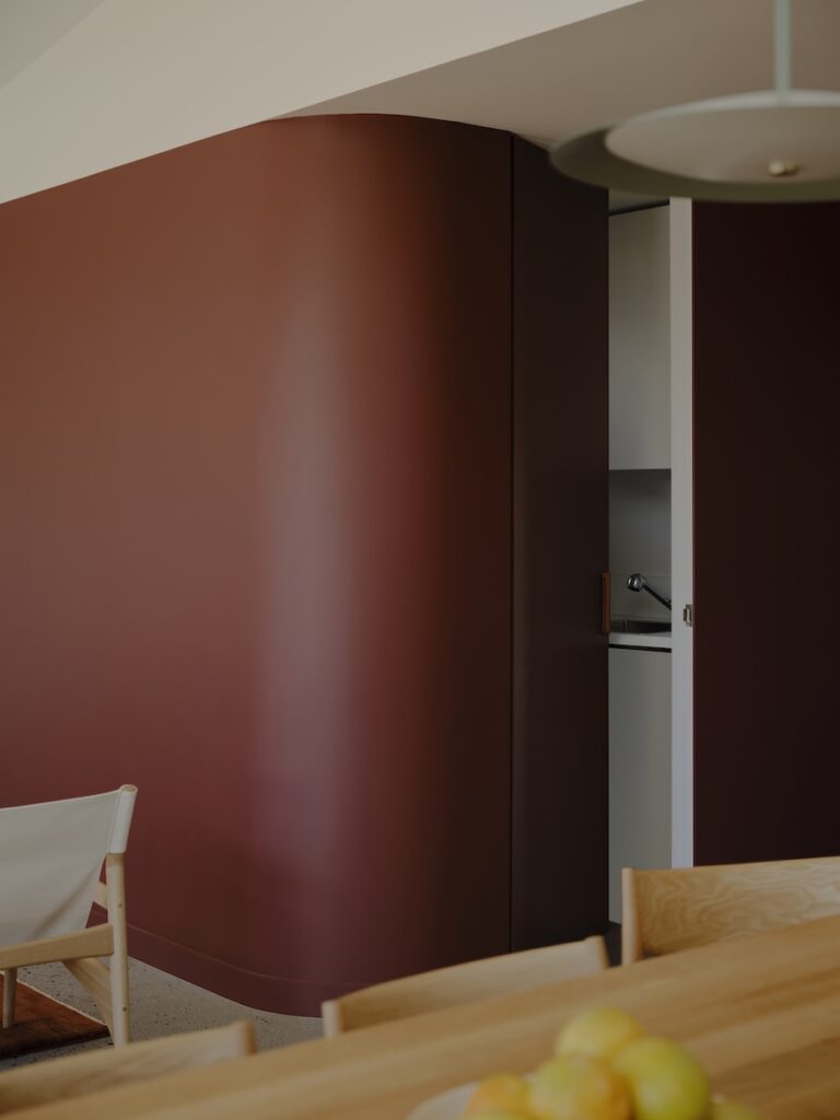 Curved internal wall concealing laundry and shaping the main living space, photographed for green magazine issue 106: Embroidered by Tom Ross.