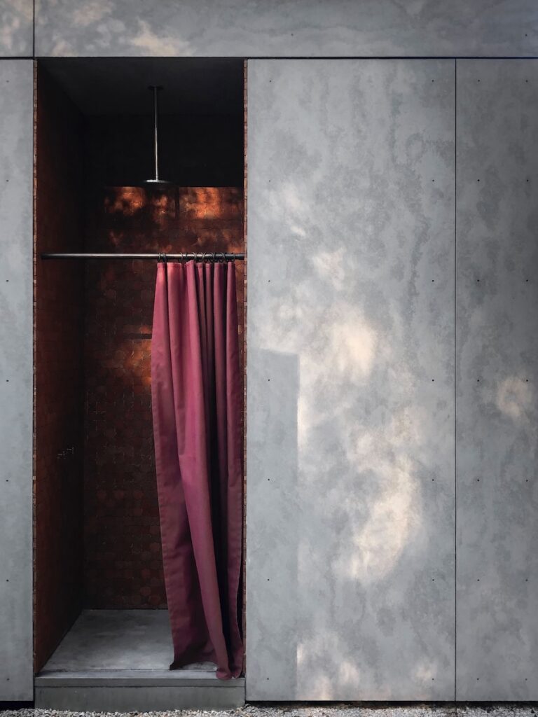 Terracotta shower with burgundy curtain opening to exterior, photographed for issue 106.