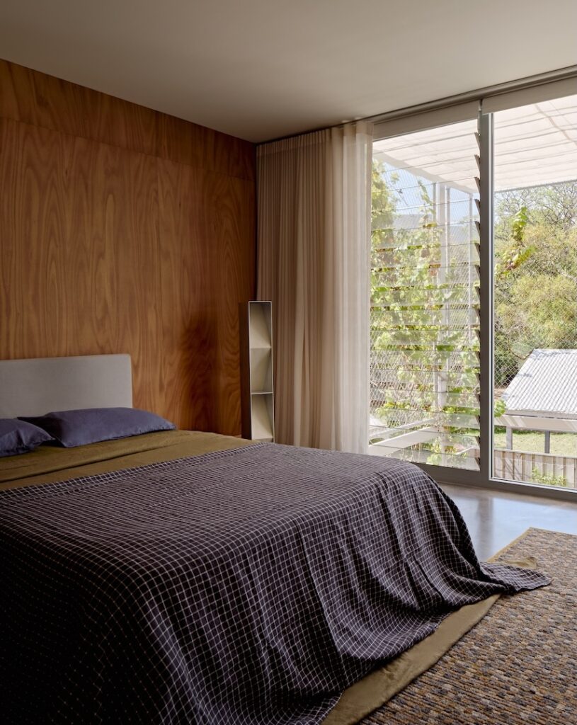 Bedroom with louvres and borrowed treetop views across neighbouring gardens, photographed for issue 106: Snuck In by Jack Lovel.