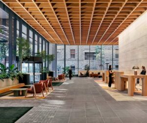 Interior view of the lobby at 500 Bourke Street in Melbourne, featuring timber joinery, planted seating areas and a coffered ceiling within a reused office building.
