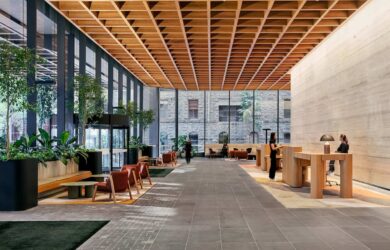 Interior view of the lobby at 500 Bourke Street in Melbourne, featuring timber joinery, planted seating areas and a coffered ceiling within a reused office building.
