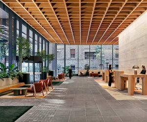 Interior view of the lobby at 500 Bourke Street in Melbourne, featuring timber joinery, planted seating areas and a coffered ceiling within a reused office building.
