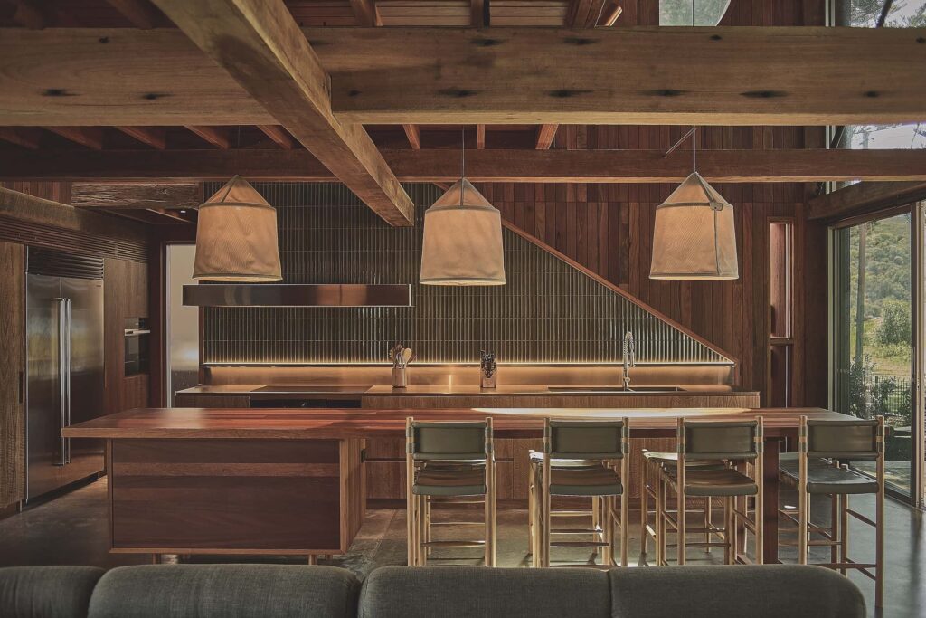 The kitchen forms the central zone, with a large island made from reclaimed teak acting as both bench and dining table, photographed for issue 107: Weather Withall by Zella Casey Brown.