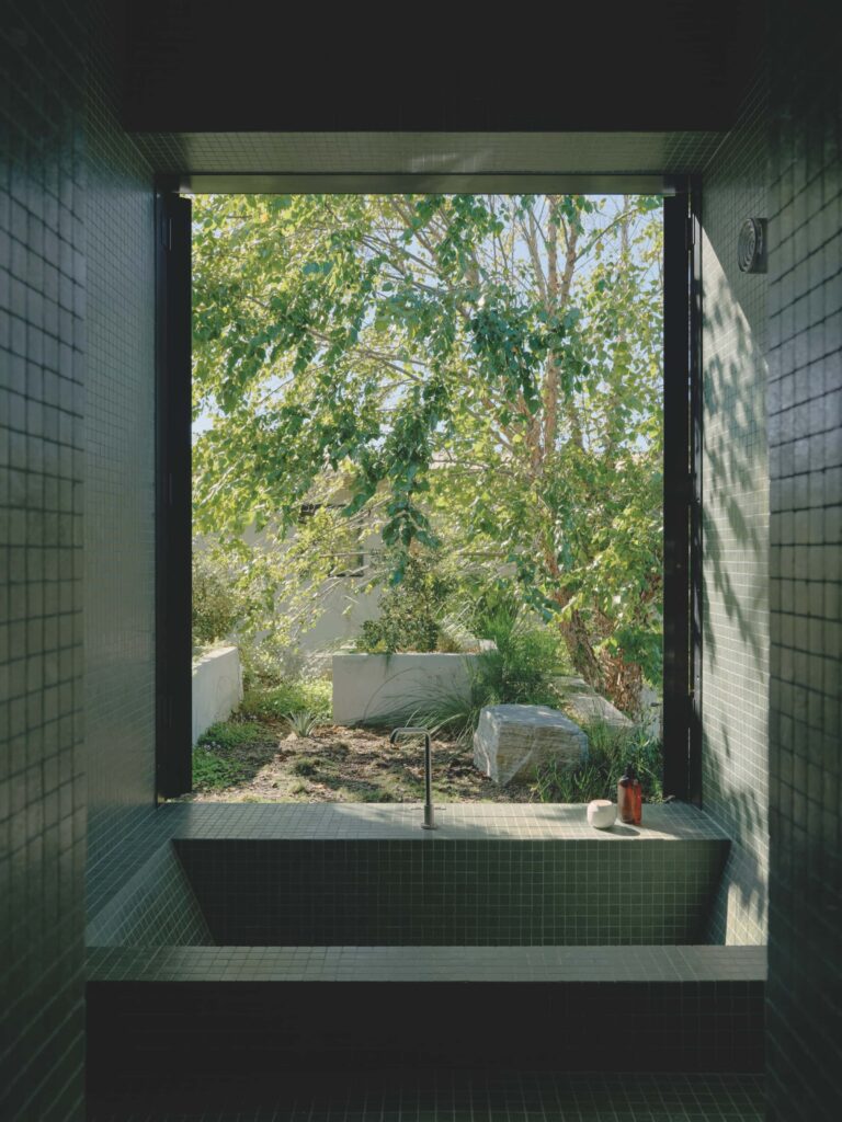 A tranquil, garden-linked master ensuite where green tiled walls and a sunken bath create an immersive outdoor-indoor retreat, photographed for issue 107: A Coastal Compact by Tom Ross.
