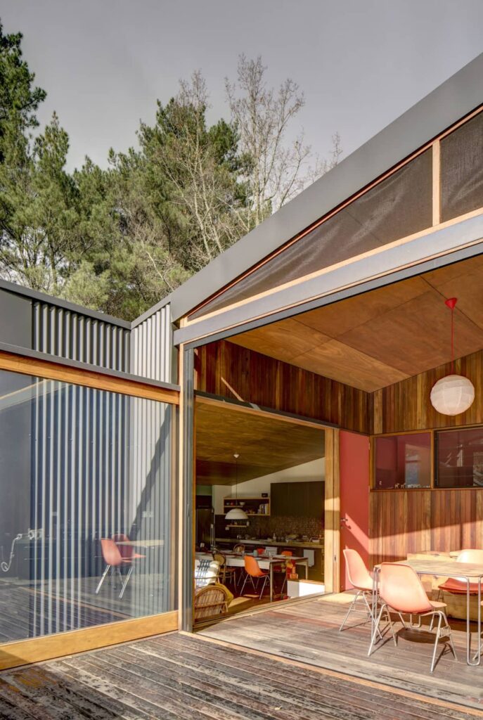 View from outdoor deck to covered deck and living room beyond at Cascading Effect, photographed by Brett Boardman.