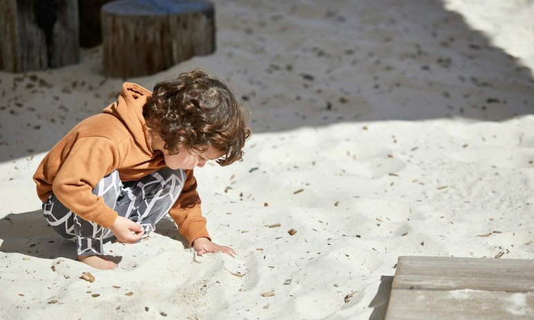 Young boy in sandpit looking through sand