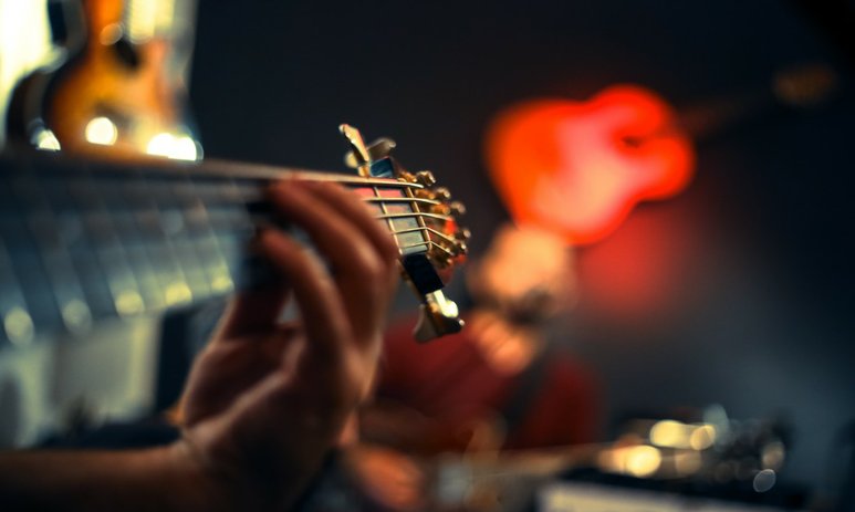 Close up of musicians guitar neck focused on the tuning pegs with blurred background