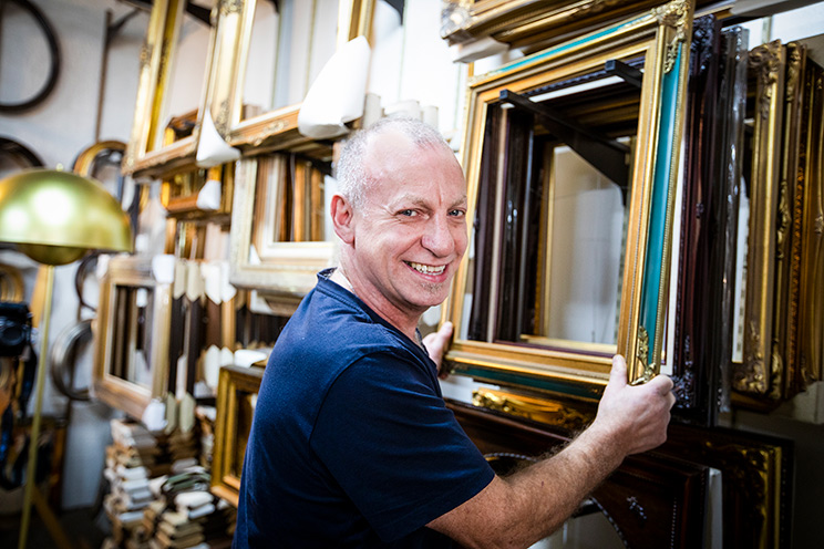 Smiling man holding picture frames