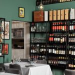 Italian restaurant interior with bottles of wine on shelves and white table cloths