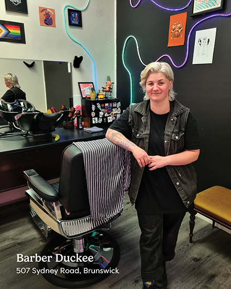 A young barber leaning on a barber's chair at Barber Duckee on Sydney Road Brunswick.