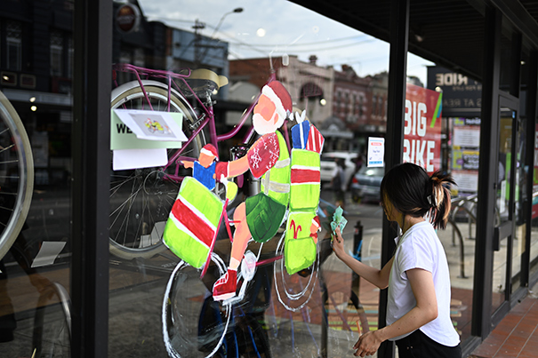 Artist painting on a shopfront window for the festive season 2024, as a part of the Festive Art on Windows program, in the Sydney Road Brunswick precinct.