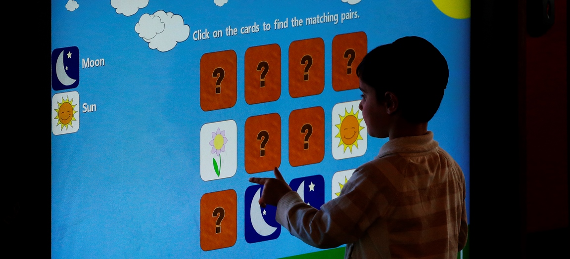 Child about 5 years old using an interactive screen display.