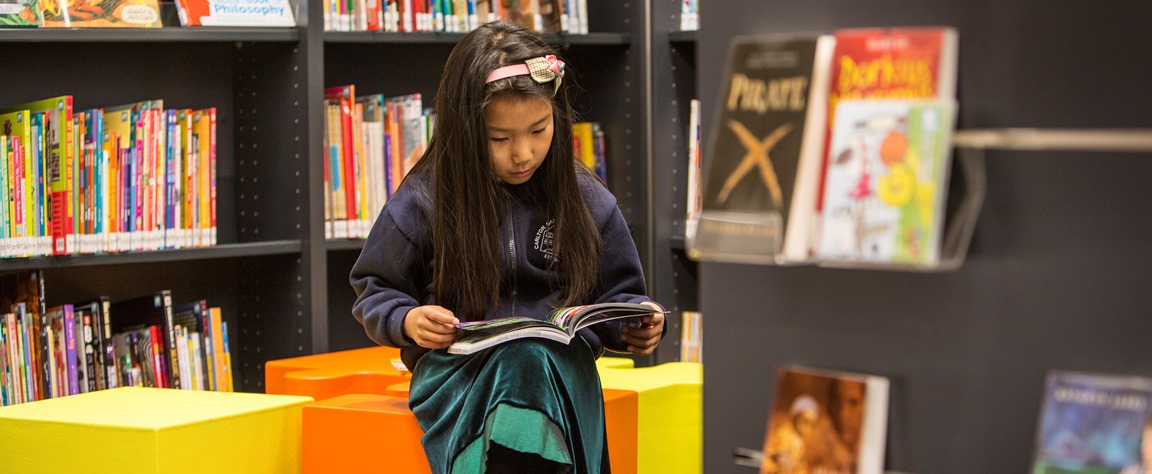 Young girl reading book sitting in a chair