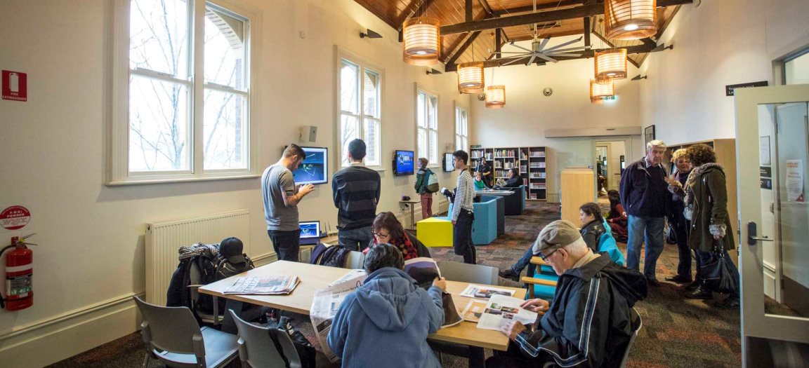 People gathered in a library, standing and at tables