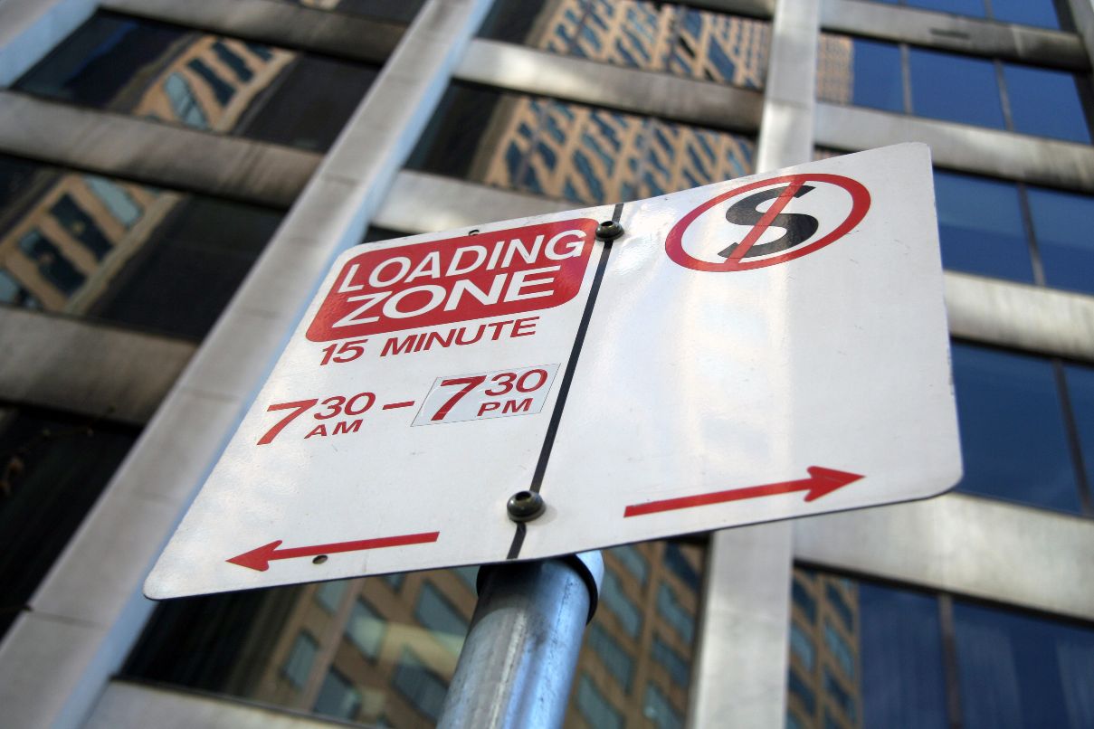 Photo of a loading zone and no standing zone sign, looking from the ground up.