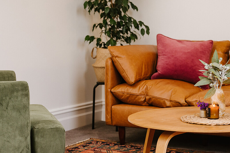 A warm brown sofa sits opposite an olive green arm chair in a psychology clinic