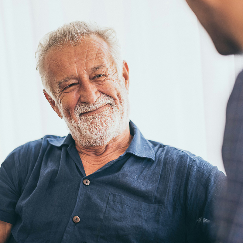An older man sits smiling with a psychologist