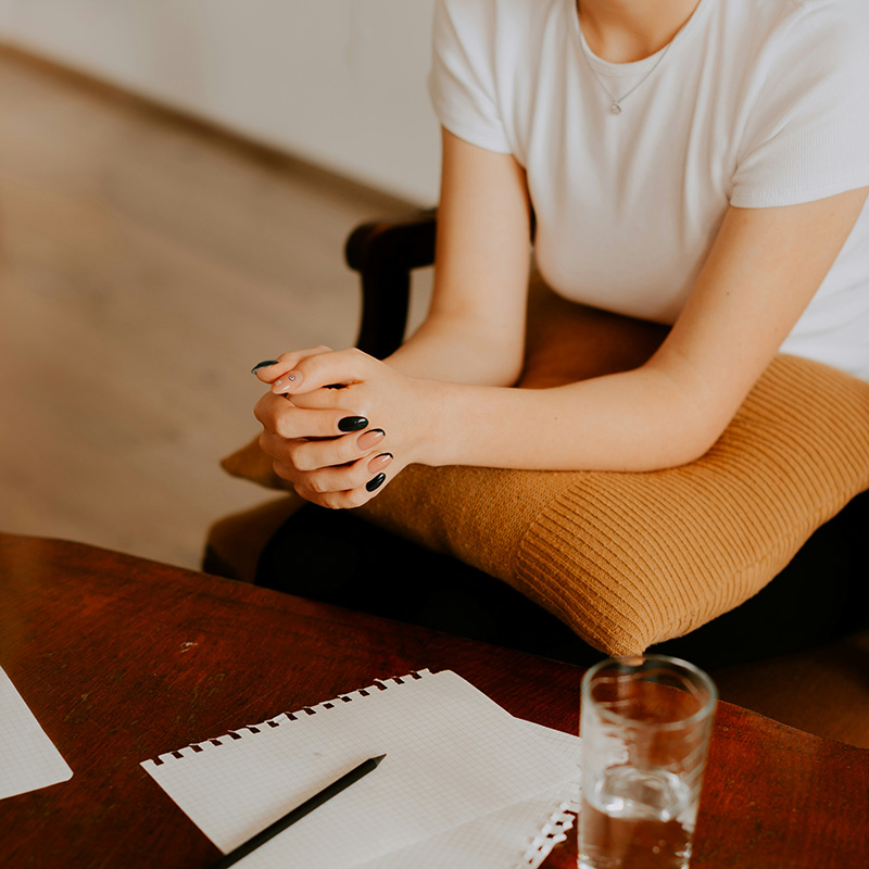 A young woman rests her elbows on a pillow on her lap while in therapy