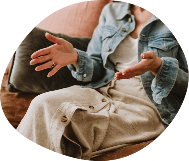 A woman sitting on a brown sofa, talking with her hands