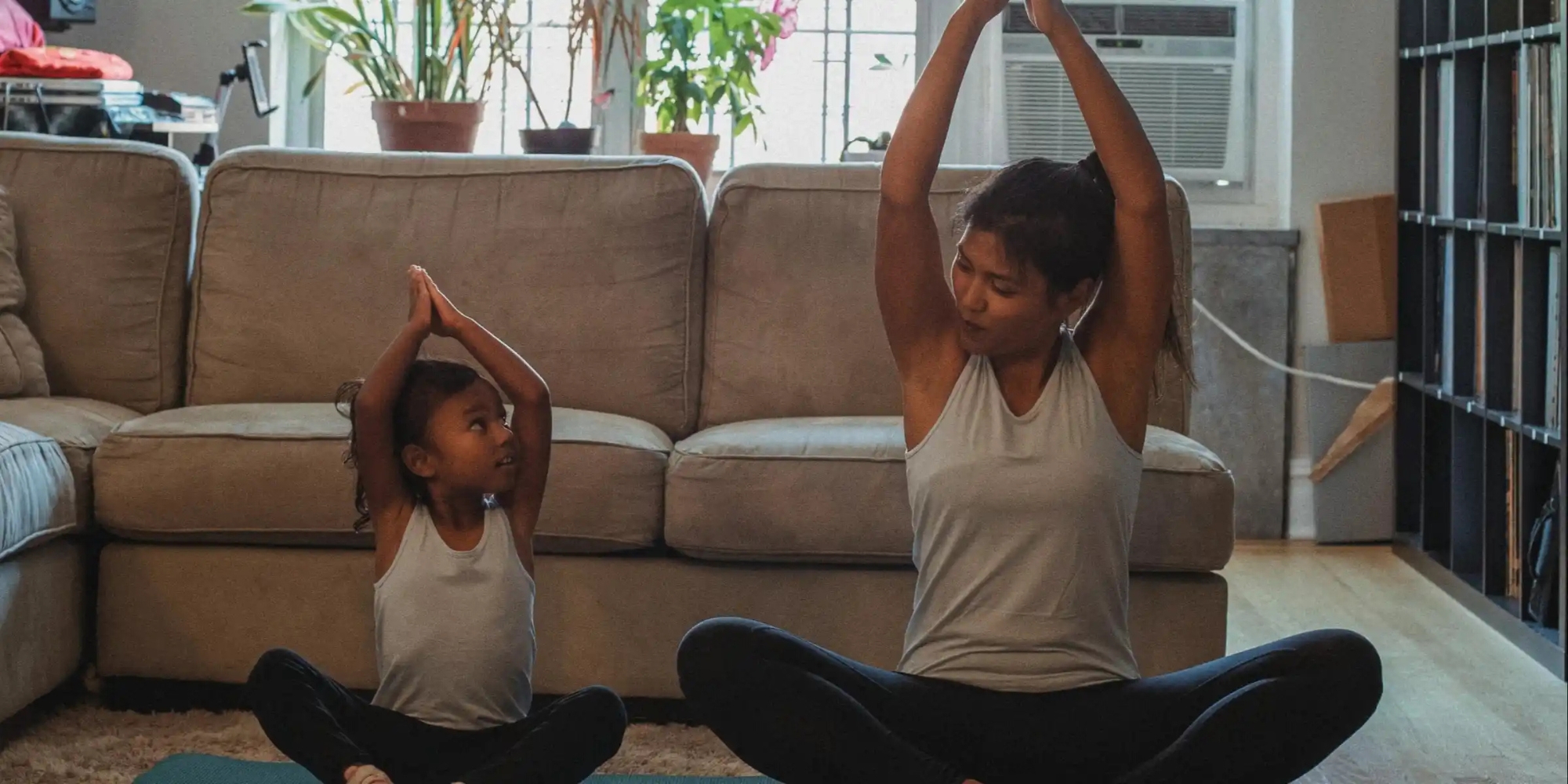 Yoga Together: Parent and Child Program banner. The banner consists of an image of a mother and her daughter sitting down doing a yoga pose in their living room.