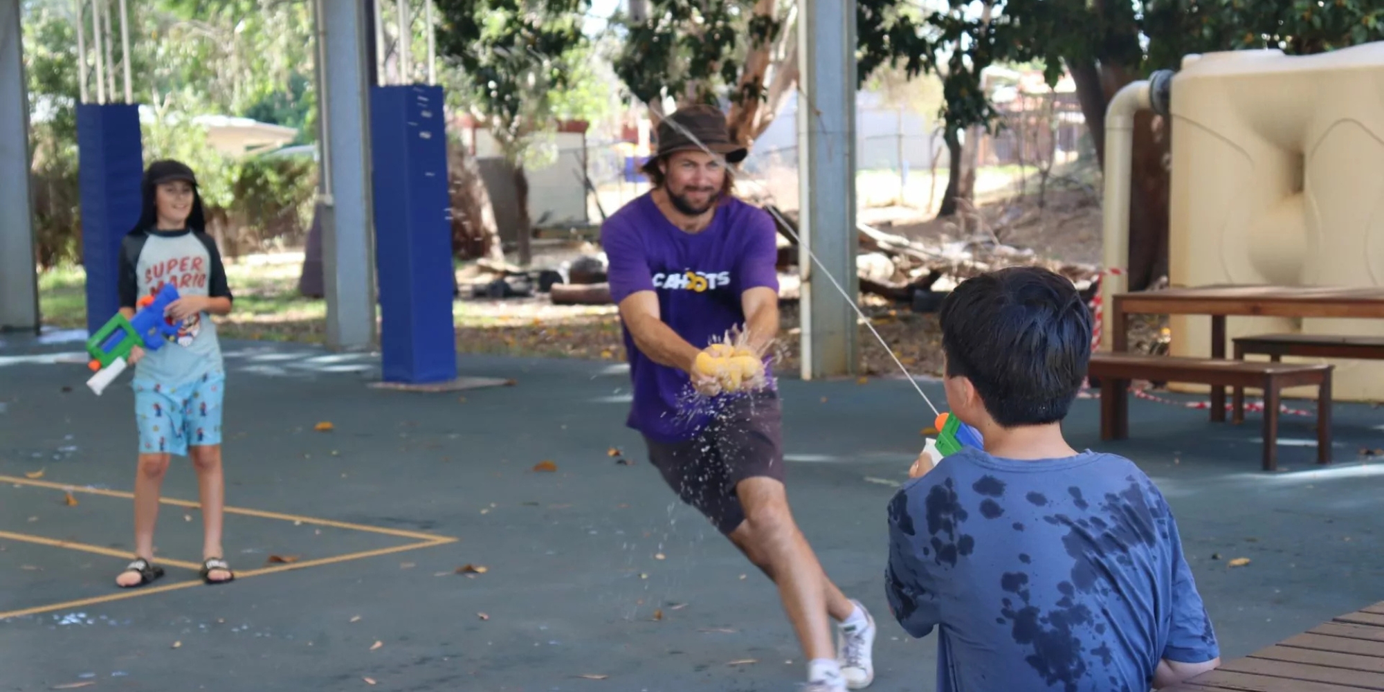 Cahoots weekend programs in Cockburn banner. The banner consists of an image of a Cahoots staff member having a water gun battle with two Cahoots participants