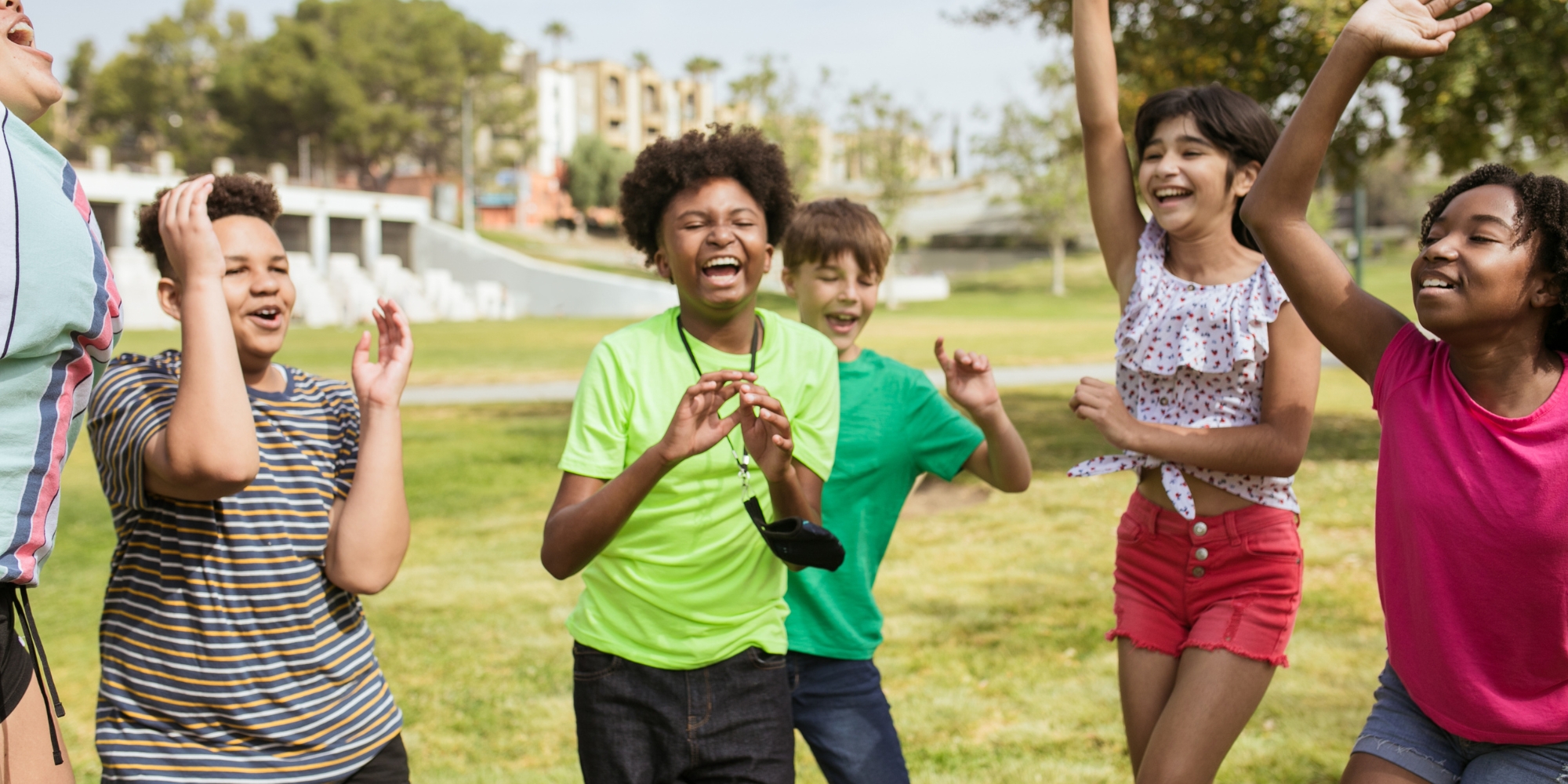 Holidays with HelpingMinds banner. The banner conists of an image of a group of children and young people cheering and smiling outside in a field