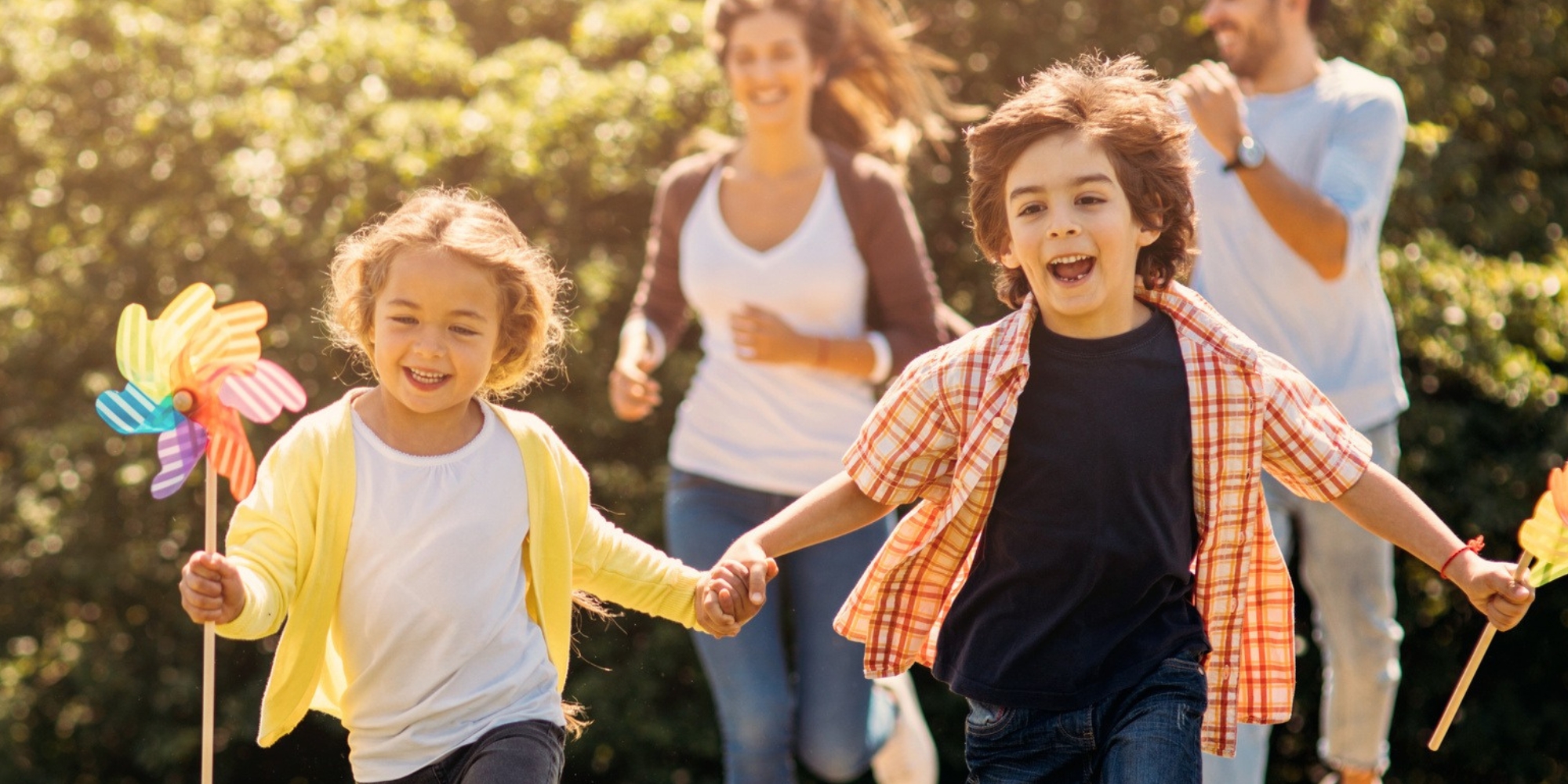 Spark group therapy program with ADHD WA banner. The banner consists of an image of a family running in a field. The children in the forefront are holding colourful fans and are holding hands while running and smiling