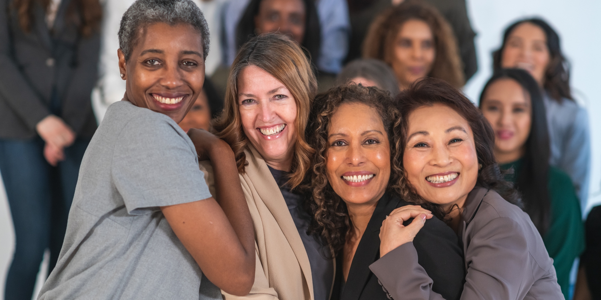 Women's health workshops in Midland with the Midland Women's Health Care Place banner. The banner consists of an image of a group of women. There are 4 women of diverse ethnicities in the forefront and they are all huddled up together and smiling