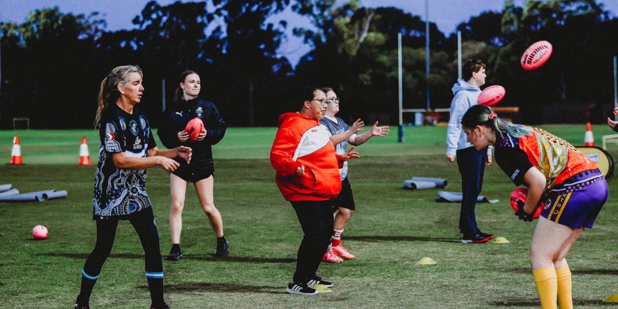 Inclusive women-only AFL: She Can Play with WA All Abilities Football Association banner. The banner consists of an image of a group of women on a Australian Football Field. They are kicking the ball to one another.