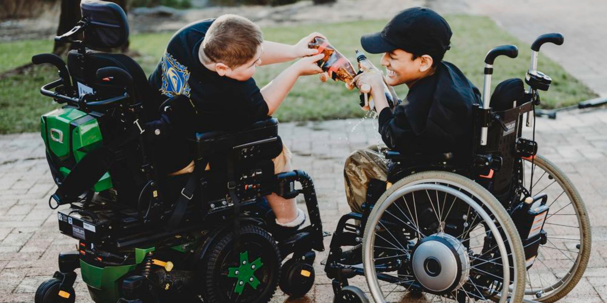 Spring Camp with Neuromuscular WA banner. The banner consists of an image of two young boys who are in sitting in wheelchairs. They are interacting and smiling at one another while sharing a beverage.