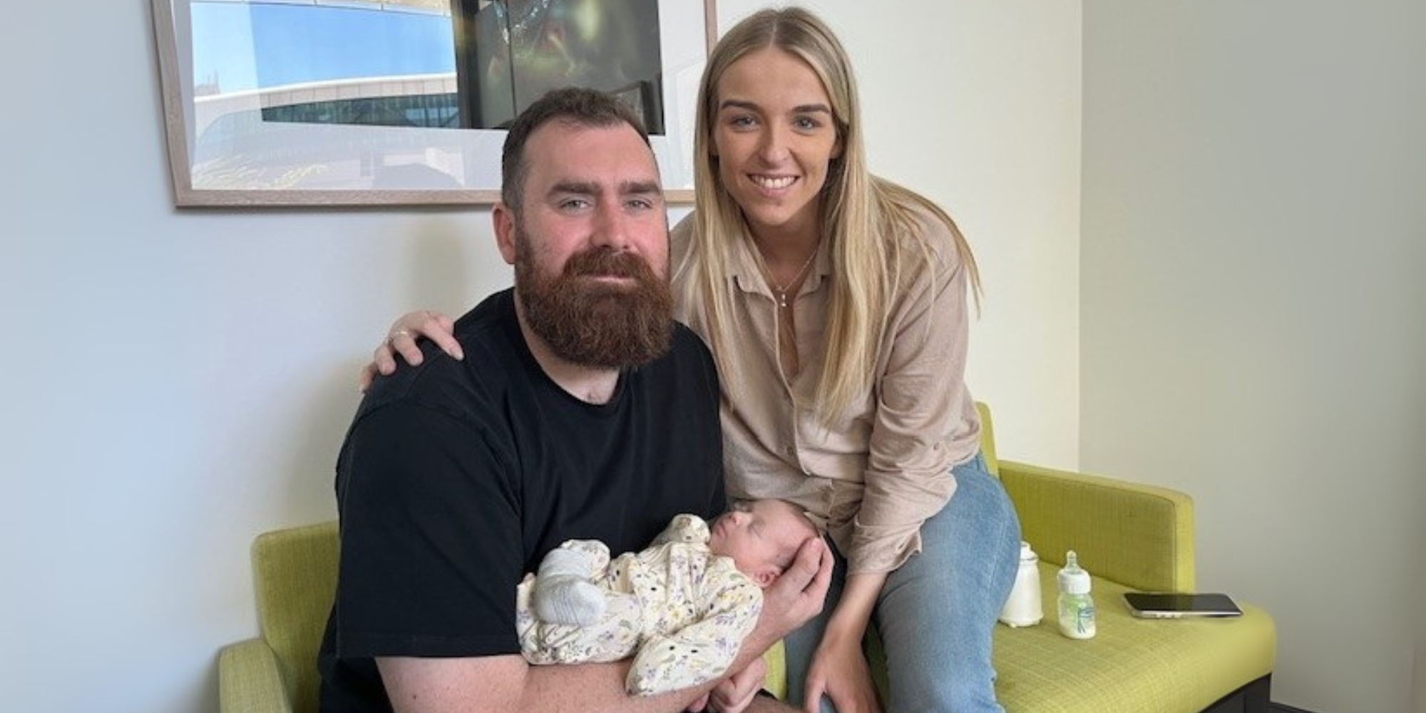 How early support is helps Samantha thrive family story banner. The banner consists of an image of a mother, father and their child. The mum and dad are sitting on green lounges and smiling at the camera. The dad is holding their new born child in his arms.
