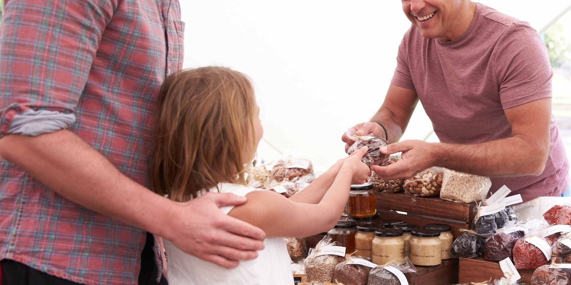 All Abilities Pop Up Market with Self Made Square and APM Communities banner. The banner consists of an image of a man handing a young girl a gift or package and smiling behind his stall.