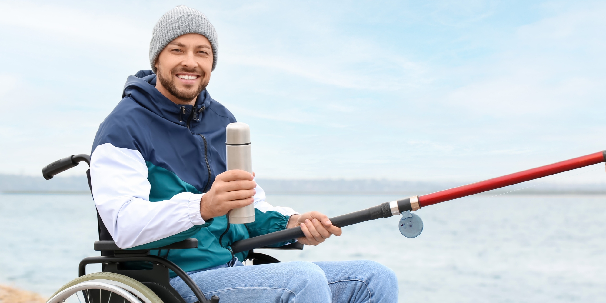 The Purely Socials: Fishing for All Abilities banner with Neuromuscular WA. The banner consists of an image of a man in wheelchair holding on to a drink bottle and fishing rod. He's wearing a beanie and winter gear and he is at the beach.