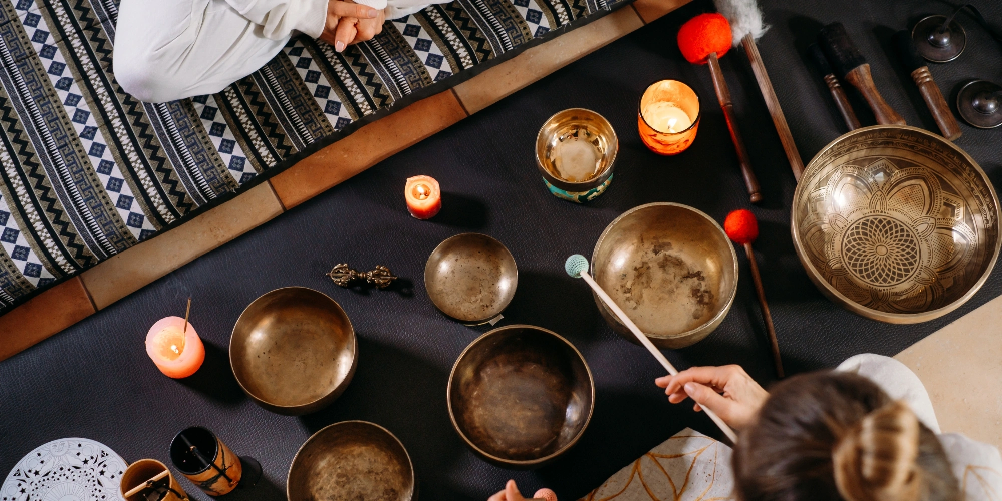 Sound Healing and Breathwork session with Carers WA banner. The banner consists of an image of bronze sound healing bowls on the floor at a birds eye view angle and two people sitting crossed legged on either side of the bowls.