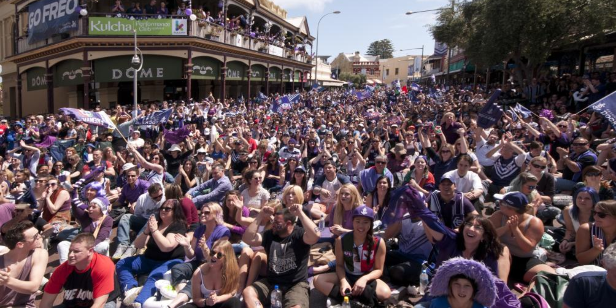 A group of diverse people watching the Fremantle Dockers at a Fremantle viewing party