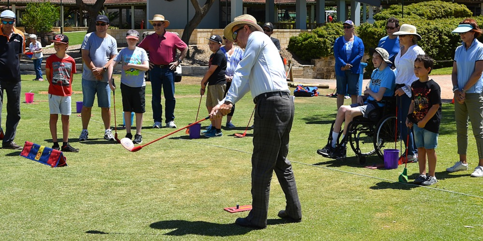 An image of a golf day with multiple families standing on the lawn with golfing equipment - Kiind's What's on activity and event guide