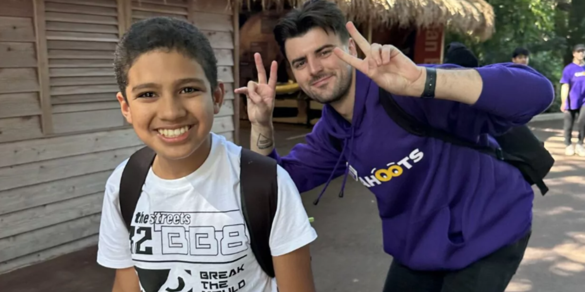 A child and a Cahoots camp leader smiling at the camera and giving the peace sign