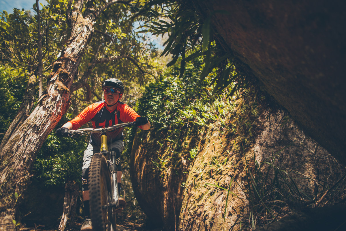 Darryll squeezes his Canyon Spectral through a big leafy boulder.