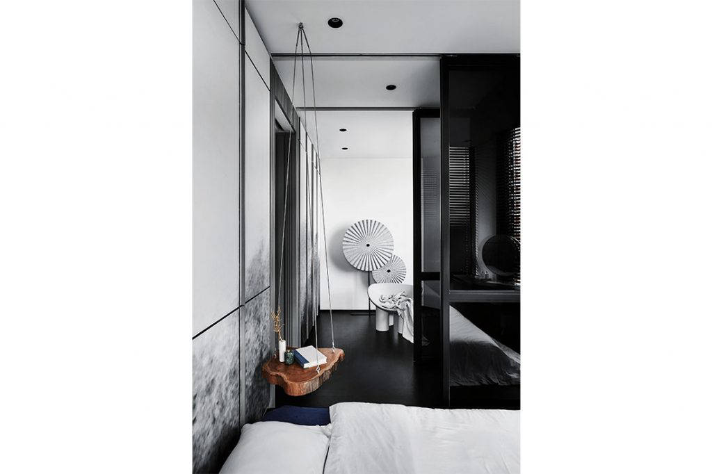  A bespoke ombre bedhead doubles as a storage wall. Across the room is a lounge area with a Roly Poly chair by Studio Toogood and a decorative Mood Screen by Grado Design, inspired by Chinese paper umbrellas. Injecting some warmth into the monochromatic space is a suspended wood slab that serves as a bedside table.