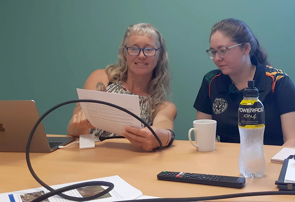 Two women reading a document about threatened ecological communities.