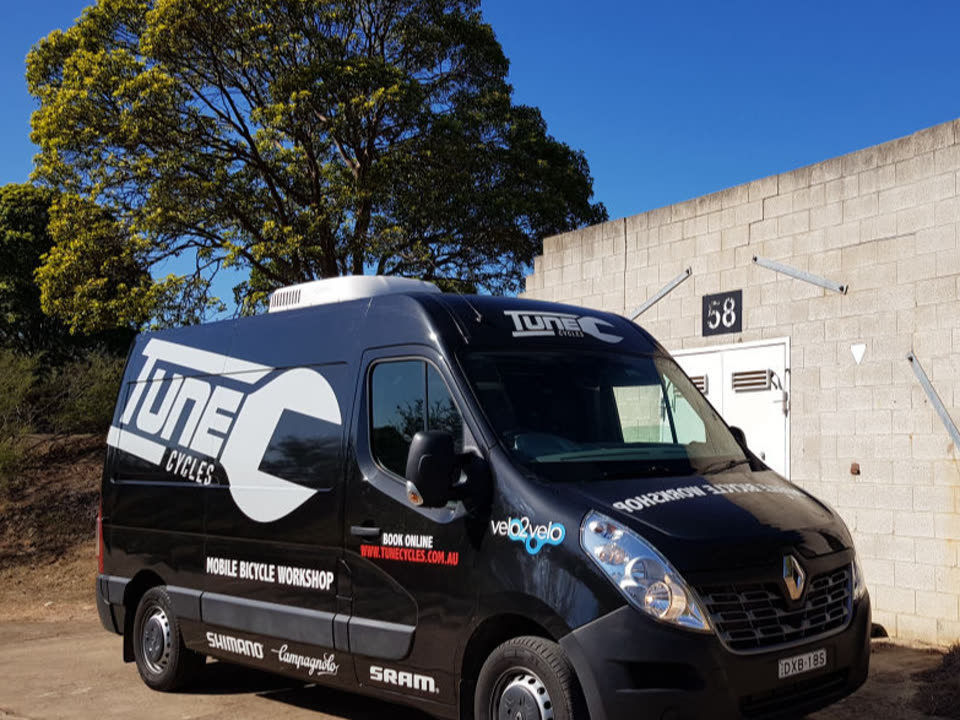 Tune Cycles black mobile workshop van parked outside a building