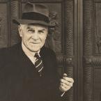 A photograph of a man standing in front of embossed bronze doors