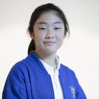 A young girl with a ponytail, wearing a blue and white uniform.